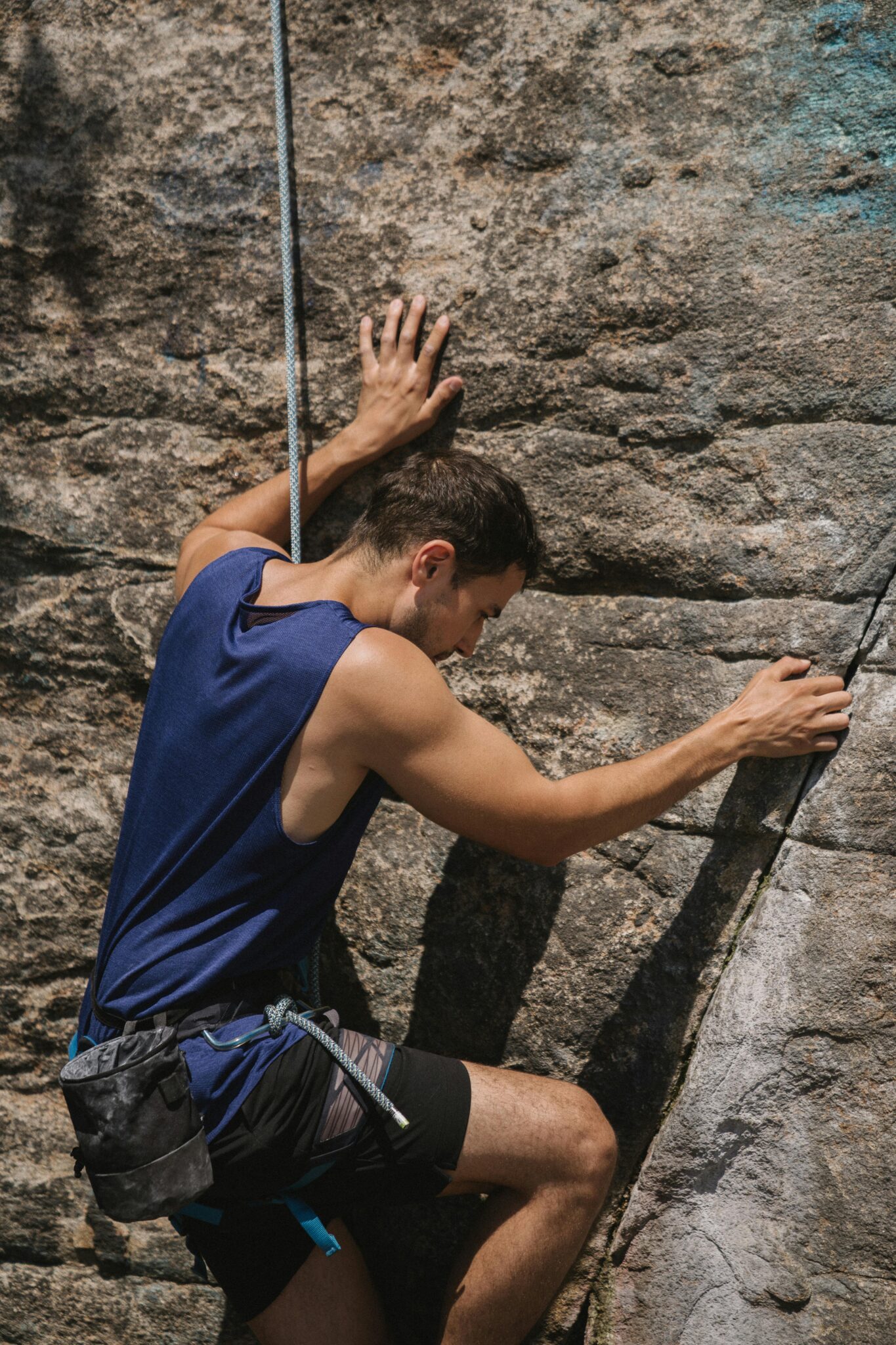 Adult male rock climber scaling a cliff with rope and harness, showcasing skills and determination.